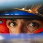 F1 pilotunun kaskı ve pist manzarası, sürüş görüşü konseptini vurguluyor