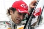 Alex Zanardi, yarış arabasında, zafer kazanmış şekilde gülümsüyor.