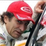 Alex Zanardi, yarış arabasında, zafer kazanmış şekilde gülümsüyor.
