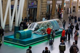 Aston Martin F1 Glenfiddich Car in a Bottle kus bakisi Kings Cross tam kurulum yesil platform kalabalik Londra 2026