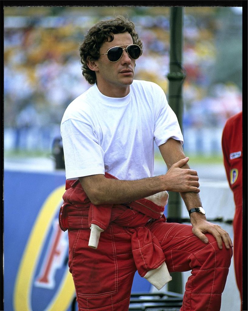 Ayrton Senna kirmizi McLaren tulumunda beyaz tisort pilot aviator gozluk bilek saati ile paddockta - dergi kapagi kalitesinde ikonik portre