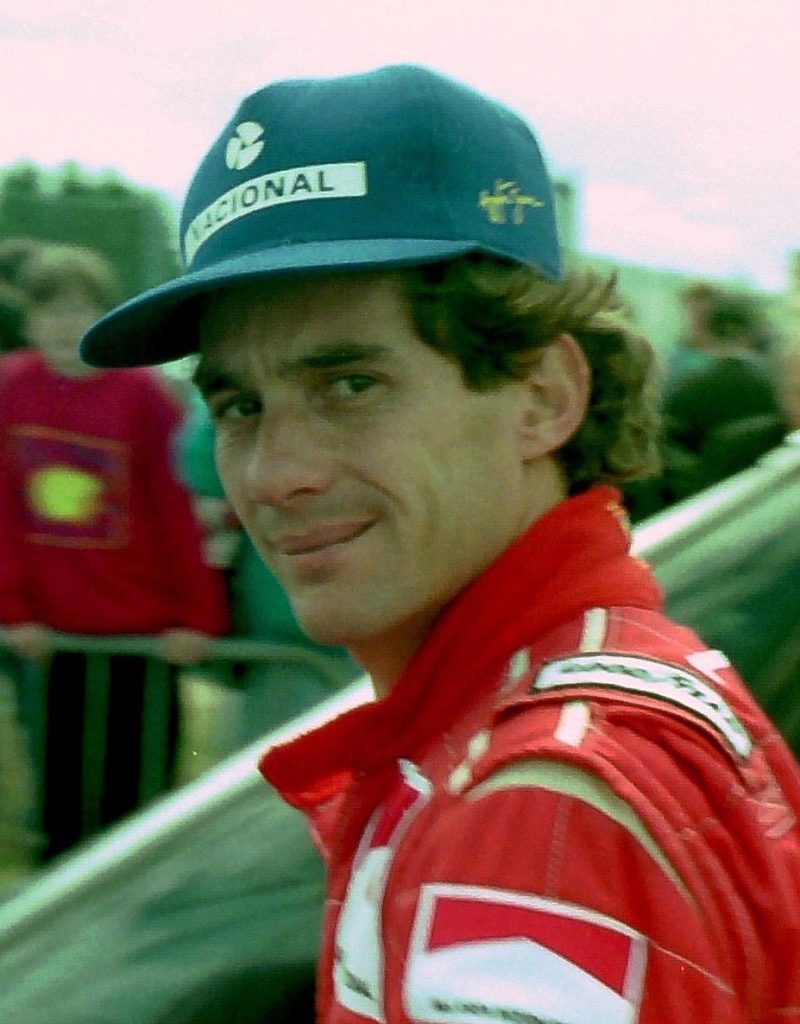 Ayrton Senna Nacional sponsorlu sapkayla McLaren Marlboro tulumunda hafif gulum - paddock candid portre Shell logo arkada