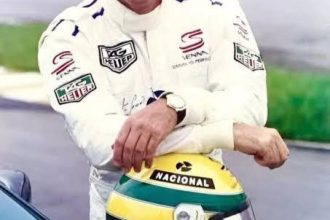 Ayrton Senna TAG Heuer Senna markalı beyaz tulumda Nacional kaskına yaslanmış büyük gülümsemeyle - F1 efsanesini en iyi özetleyen fotoğraf