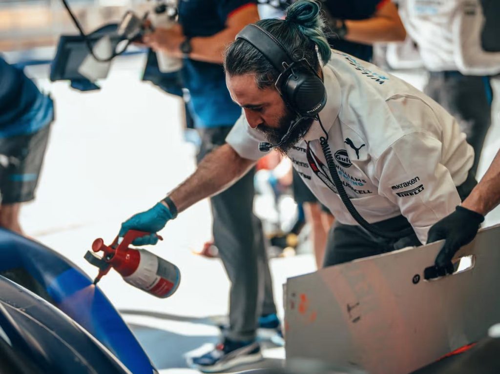 Williams Racing mekanisyen flow viz boyayı spreyle aracın üzerine püskürtüyor pit lane Gulf Kraken Duracell
